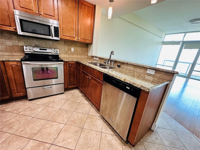 kitchen featuring light tile patterned flooring, sink, kitchen peninsula, pendant lighting, and stainless steel appliances