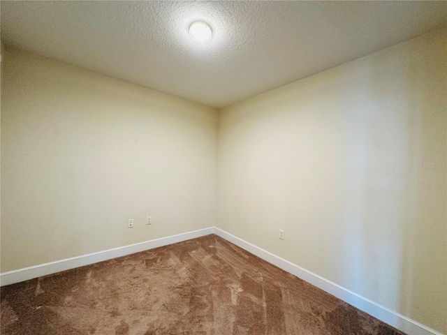 carpeted empty room featuring a textured ceiling