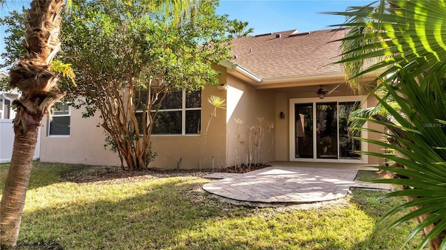 back of property with ceiling fan, a yard, and a patio