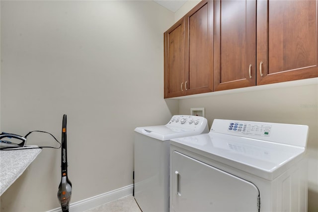 laundry area with light tile patterned floors, washer and clothes dryer, and cabinets