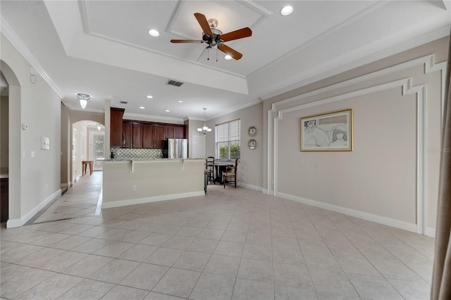 kitchen featuring stainless steel refrigerator, a kitchen bar, a tray ceiling, and pendant lighting