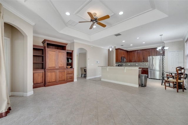 kitchen with pendant lighting, appliances with stainless steel finishes, a kitchen breakfast bar, ornamental molding, and a raised ceiling