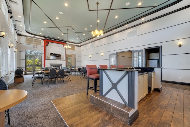 kitchen with decorative light fixtures, a center island, a large fireplace, white cabinets, and a high ceiling