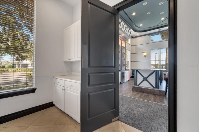 kitchen with light tile patterned flooring, a towering ceiling, and white cabinets