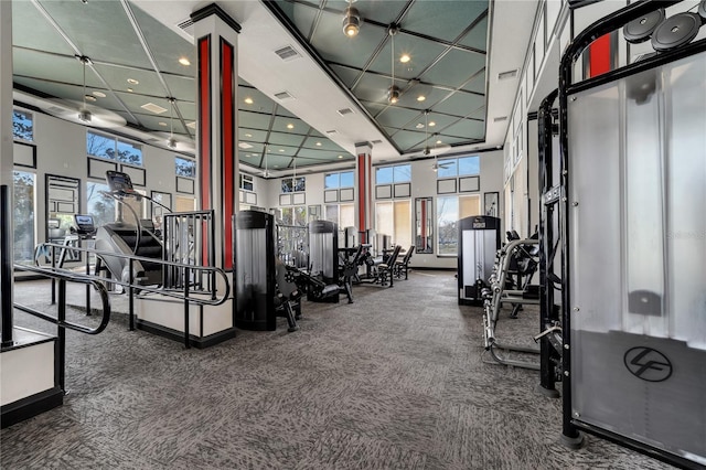 exercise room featuring a towering ceiling, a wealth of natural light, and ornate columns