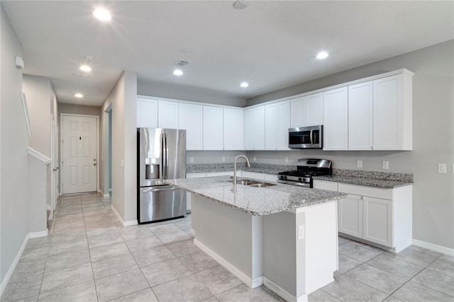 15574 Murcott Blossom Blvd, Winter Garden, FL 34787 - kitchen with appliances with stainless steel finishes, a center island with sink, white cabinetry, light tile patterned flooring, and light stone counters
