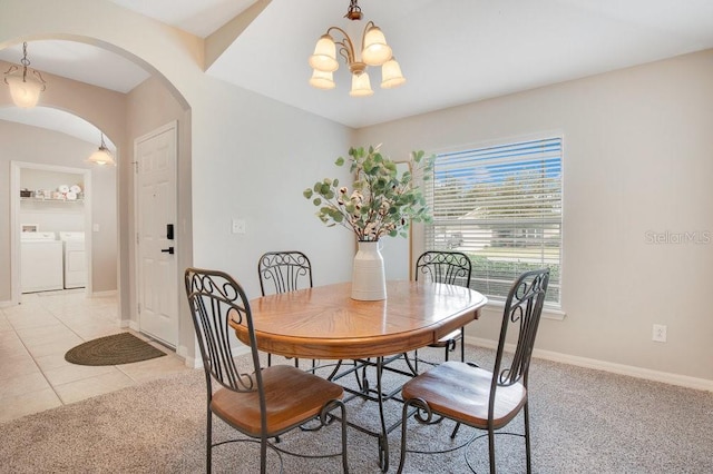 tiled dining room featuring a notable chandelier and independent washer and dryer