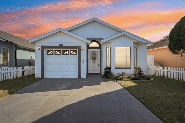 ranch-style home featuring a garage and a lawn