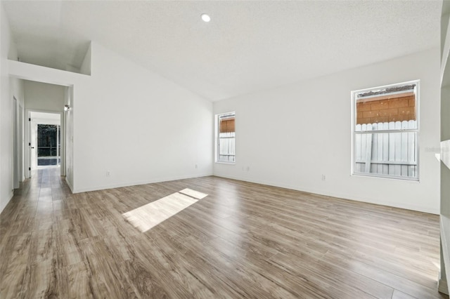 spare room featuring vaulted ceiling, light hardwood / wood-style flooring, and a textured ceiling