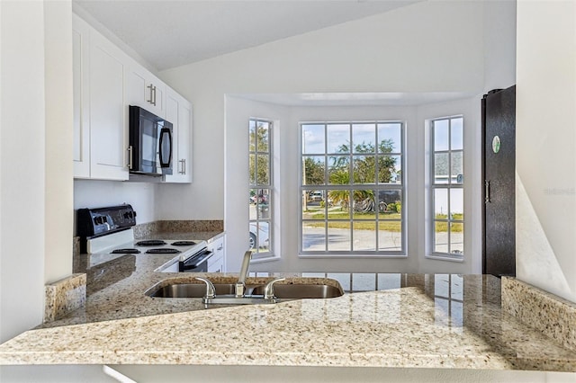 kitchen featuring lofted ceiling, sink, light stone counters, range with electric stovetop, and white cabinets