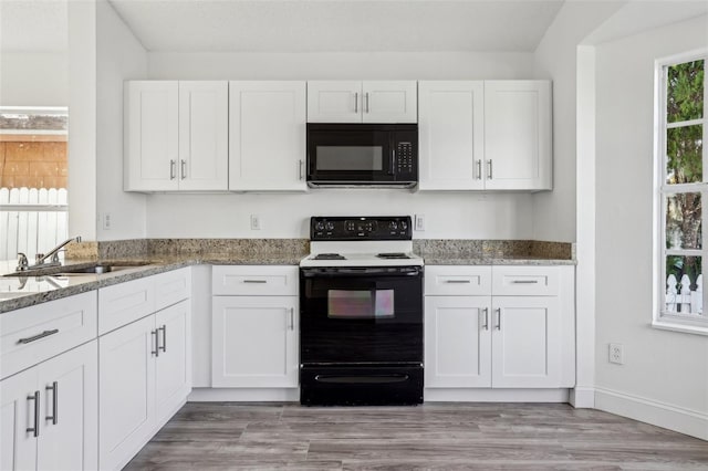 kitchen with stone counters, sink, electric range oven, and white cabinets