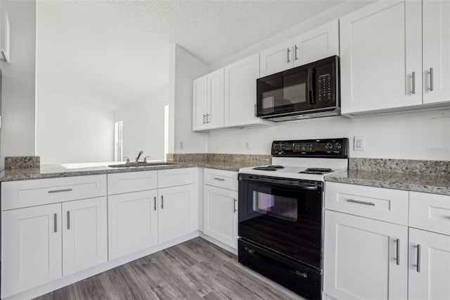 kitchen with a textured ceiling, light wood-type flooring, range with electric stovetop, light stone countertops, and white cabinets