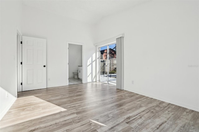 empty room with high vaulted ceiling and light wood-type flooring