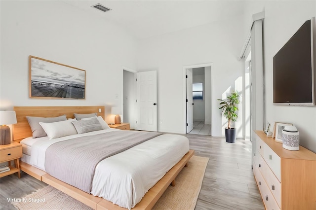 bedroom featuring a high ceiling and light wood-type flooring