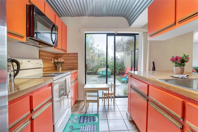 kitchen with wood counters, light tile patterned flooring, and white range with electric cooktop