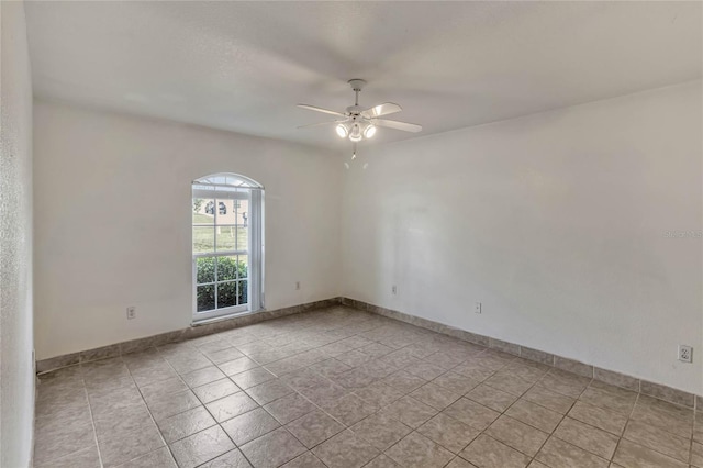 empty room featuring light tile patterned floors, baseboards, and a ceiling fan