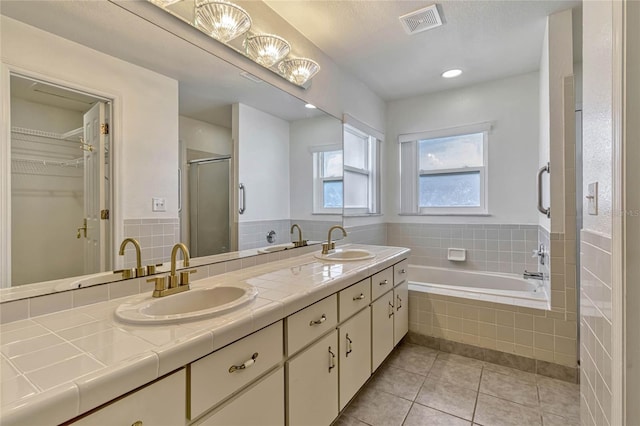 full bath with a shower stall, visible vents, a walk in closet, and a sink