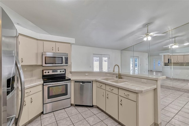 kitchen with a sink, open floor plan, light countertops, appliances with stainless steel finishes, and cream cabinetry