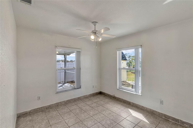 spare room featuring a healthy amount of sunlight, ceiling fan, visible vents, and baseboards