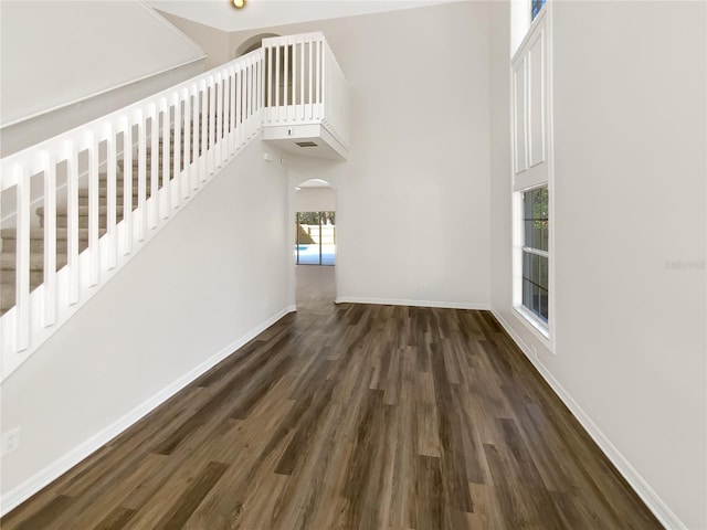 unfurnished living room with dark hardwood / wood-style flooring and a high ceiling