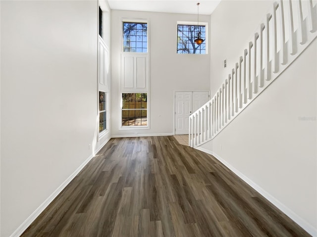 entrance foyer featuring a towering ceiling, a wealth of natural light, and dark hardwood / wood-style floors