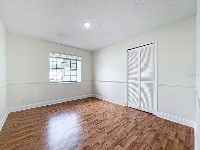 1970 Larkwood Dr, Apopka, FL 32703 - unfurnished bedroom with a textured ceiling, wood finished floors, a closet, and baseboards