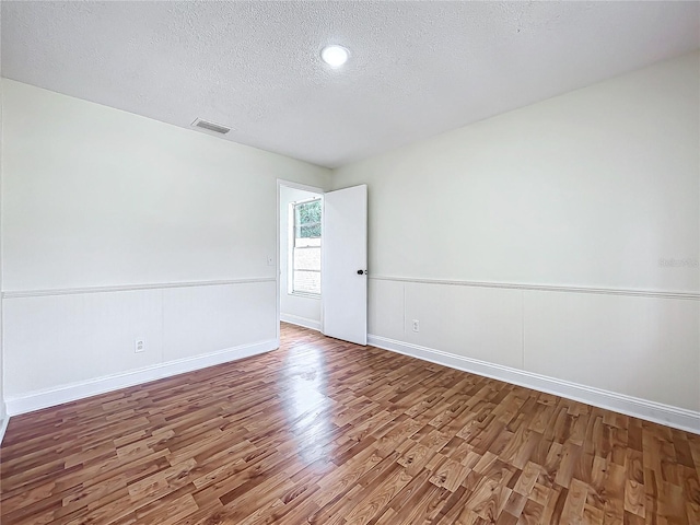 1970 Larkwood Dr, Apopka, FL 32703 - spare room with visible vents, baseboards, a textured ceiling, wainscoting, and wood finished floors