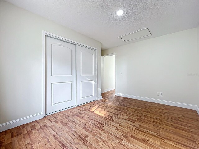 1970 Larkwood Dr, Apopka, FL 32703 - unfurnished bedroom featuring light wood-style flooring, a textured ceiling, a closet, and baseboards