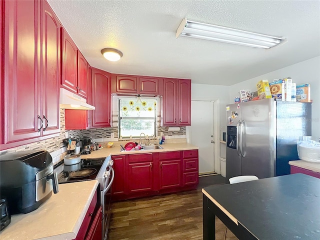 kitchen with sink, a textured ceiling, dark hardwood / wood-style floors, stainless steel appliances, and tasteful backsplash