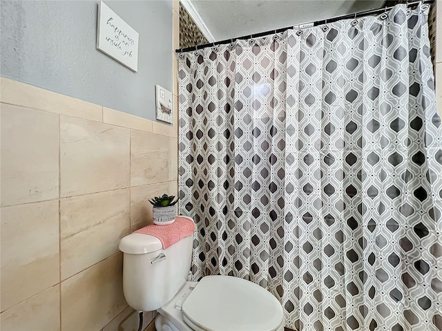 bathroom with a shower with curtain, tile walls, and toilet