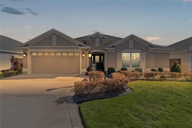 view of front of home with a garage and a lawn