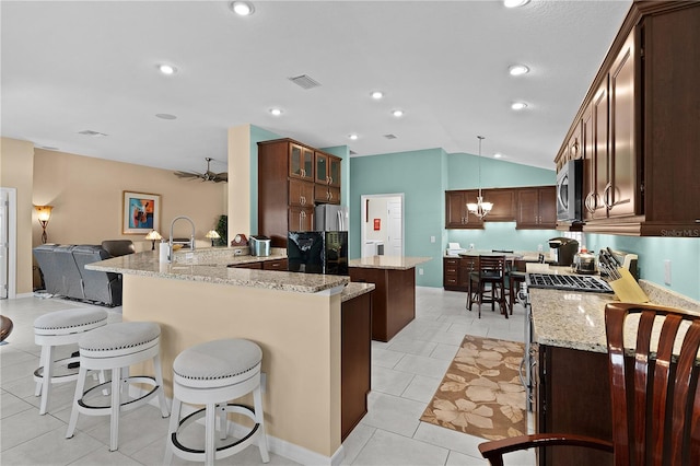 kitchen with appliances with stainless steel finishes, a kitchen bar, decorative light fixtures, vaulted ceiling, and kitchen peninsula