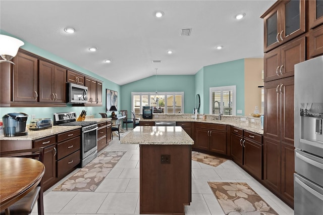 kitchen with sink, hanging light fixtures, stainless steel appliances, a kitchen island, and kitchen peninsula