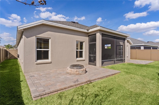 rear view of house featuring an outdoor fire pit, a yard, a patio, and a sunroom