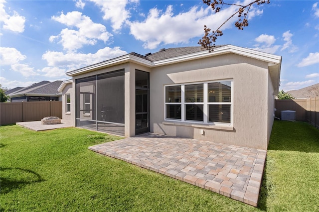 back of house featuring a sunroom, a patio, a fire pit, and a lawn