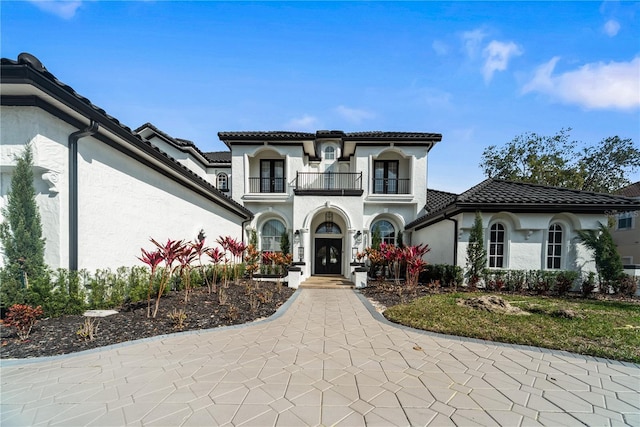 mediterranean / spanish house featuring a balcony, stucco siding, a garage, and a tiled roof