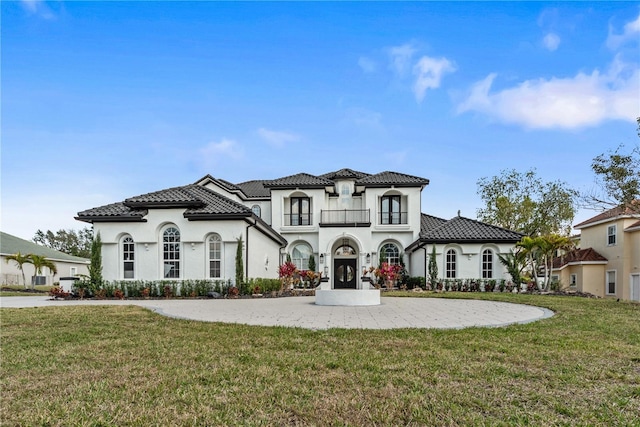 mediterranean / spanish-style house featuring a balcony, stucco siding, a tile roof, and a front yard