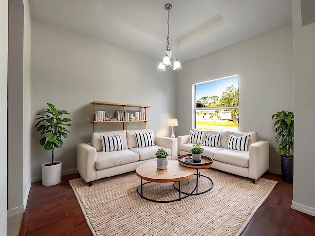 living room featuring a raised ceiling, wood-type flooring, and an inviting chandelier