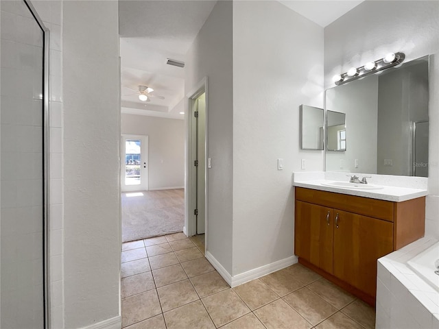 bathroom featuring ceiling fan, vanity, a tray ceiling, tiled bath, and tile patterned floors