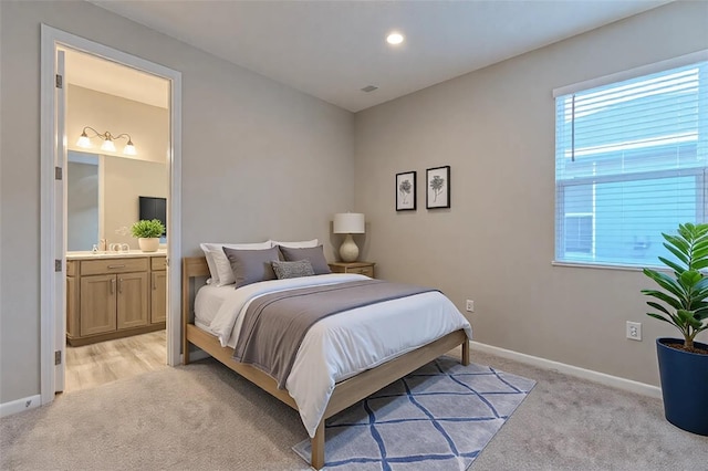 bedroom with multiple windows, connected bathroom, and light carpet