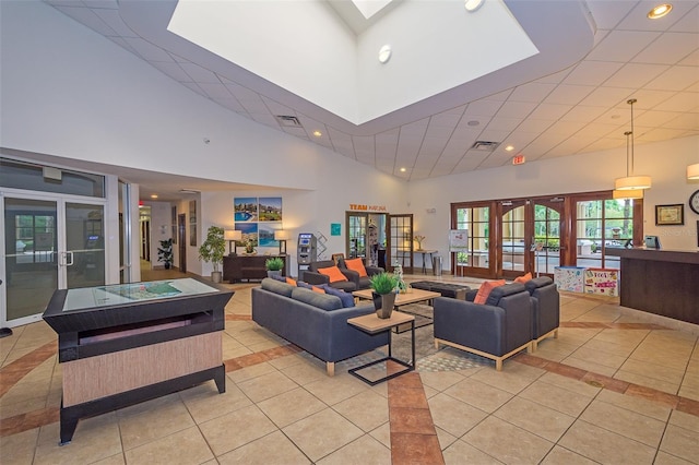 living room with a skylight, a high ceiling, light tile patterned floors, and french doors