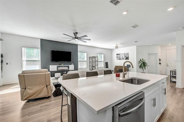 kitchen featuring white cabinetry, dishwasher, sink, an island with sink, and light hardwood / wood-style floors