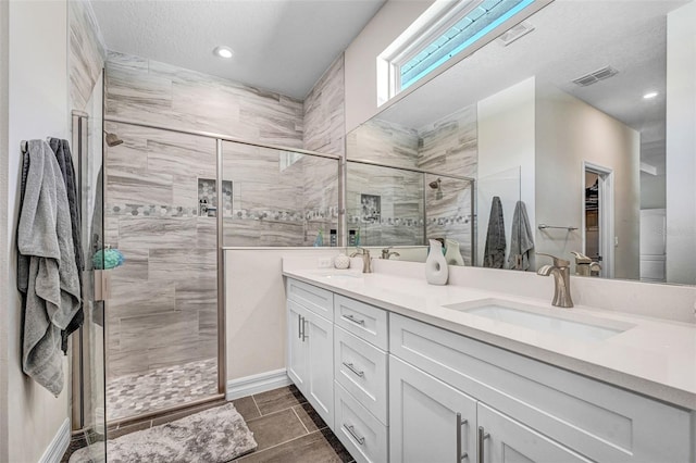 bathroom featuring vanity, an enclosed shower, and a textured ceiling