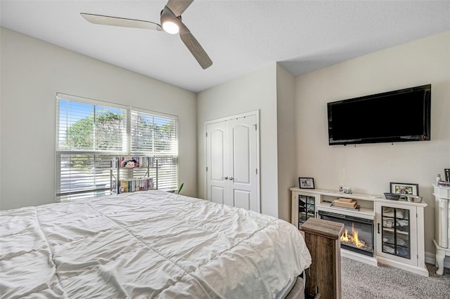 carpeted bedroom with a textured ceiling, a closet, and ceiling fan