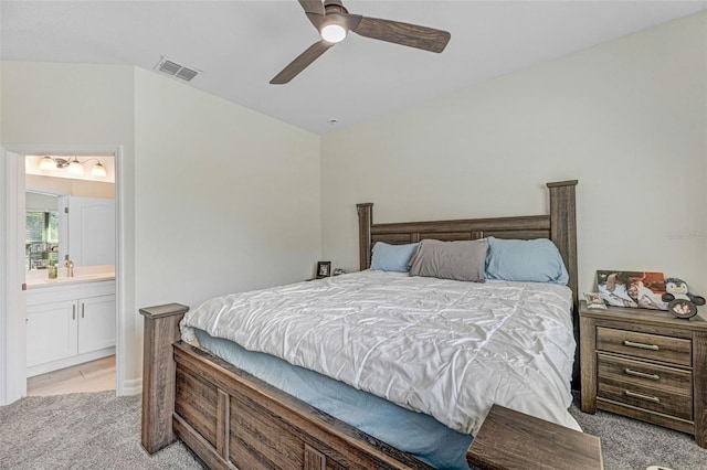 carpeted bedroom with vaulted ceiling, ceiling fan, and ensuite bath