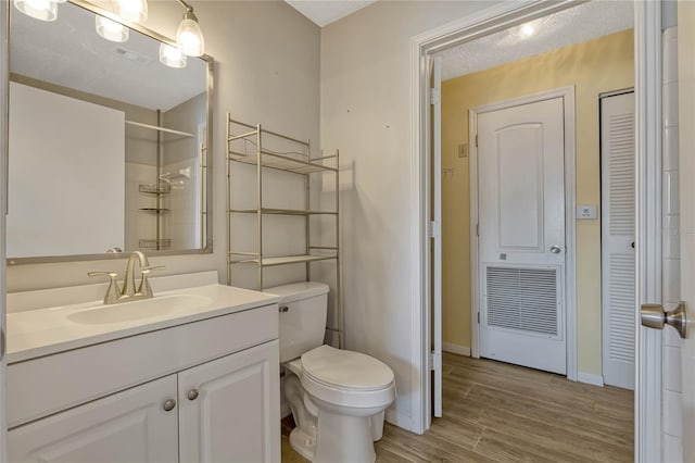 bathroom with hardwood / wood-style floors, vanity, toilet, and walk in shower