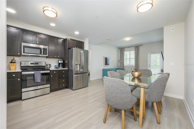 kitchen with dark brown cabinetry, stainless steel appliances, light hardwood / wood-style floors, and a textured ceiling