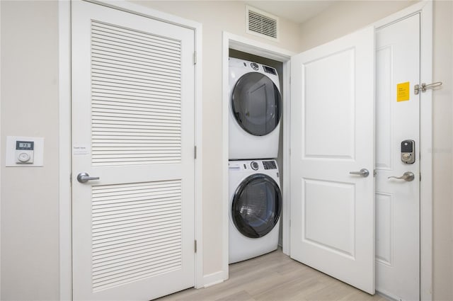 clothes washing area with stacked washing maching and dryer and light hardwood / wood-style floors