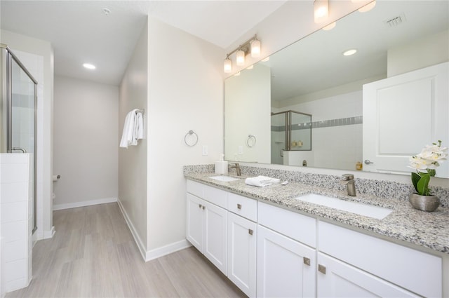 bathroom featuring vanity, hardwood / wood-style flooring, a shower with shower door, and toilet