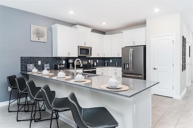 kitchen featuring white cabinetry, stainless steel appliances, a kitchen breakfast bar, and kitchen peninsula